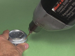 Drilling a hole in the edge of the can for air to leave while the alcohol stove is being filled.
