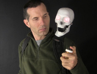 Shoulder mounted Arduino controlled skull in better lighting 
      showing the backpack straps and the hand control.