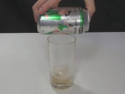 Emptying the soda can into a glass by holding one of the holes above the glass.
