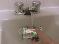 Holding the can under a faucet with one of the holes held in the flow of the water.