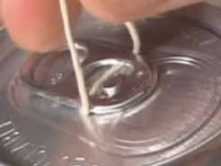 Showing that the string under the tab is lined up with the circle in the center of the top of the soda can.