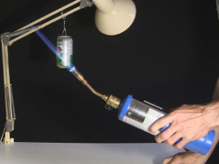 Wide view of the torch flame heating up the bottom of the soda can.