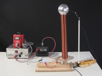 Small spark gap Tesla coil with flat plate capacitor that
      appears as a horizontal board at the base of the Tesla coil.